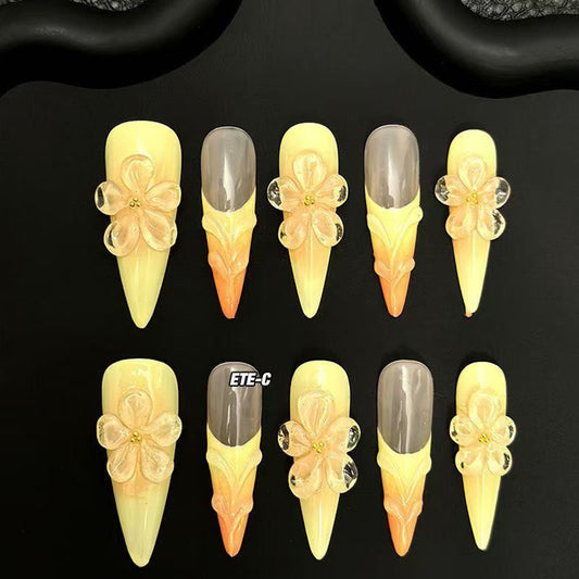 Sunset Blossom Claws set of 10 stiletto-shaped press-on nails featuring a dreamy ombre transition from soft buttery yellow at the tips to warm peach-orange at the cuticles