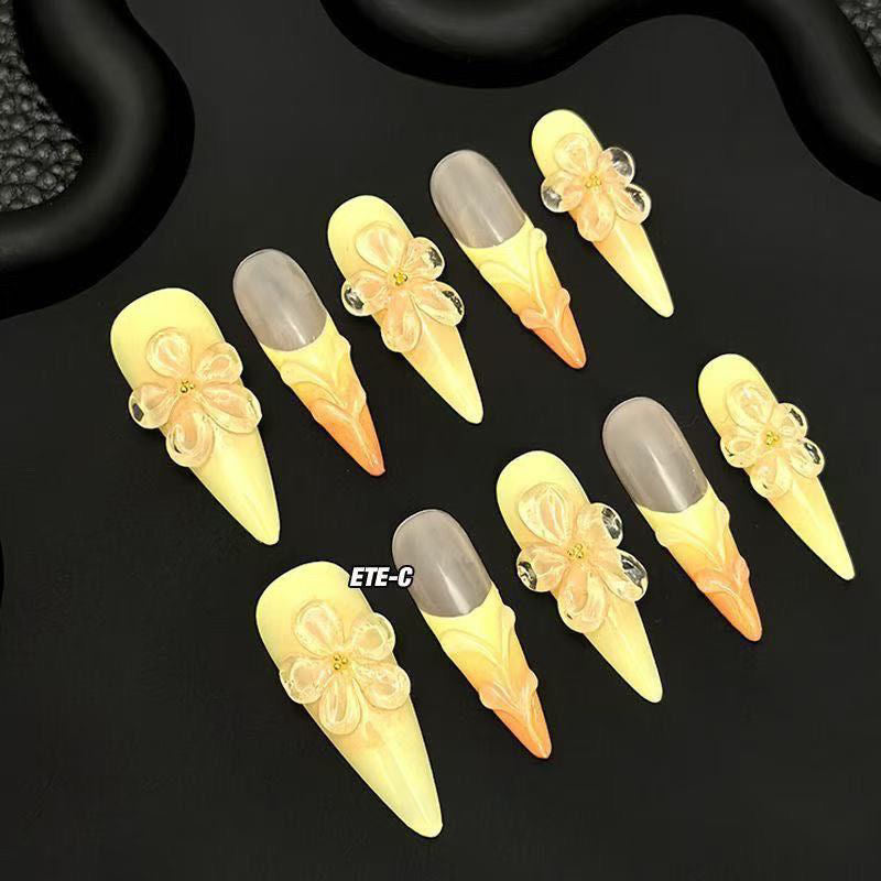 Sunset Blossom Claws set of 10 stiletto-shaped press-on nails featuring a dreamy ombre transition from soft buttery yellow at the tips to warm peach-orange at the cuticles
