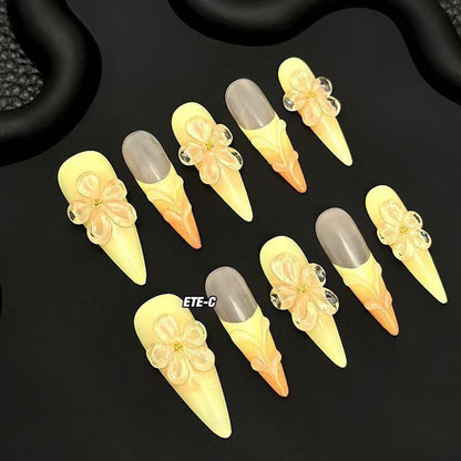 Sunset Blossom Claws set of 10 stiletto-shaped press-on nails featuring a dreamy ombre transition from soft buttery yellow at the tips to warm peach-orange at the cuticles