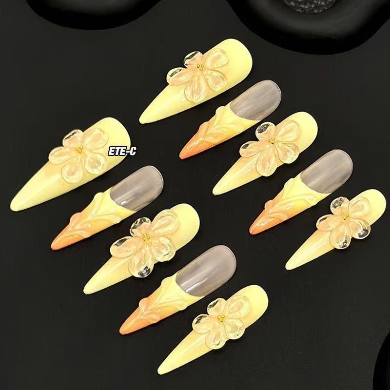 Sunset Blossom Claws set of 10 stiletto-shaped press-on nails featuring a dreamy ombre transition from soft buttery yellow at the tips to warm peach-orange at the cuticles