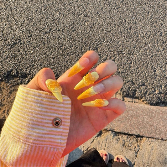Sunset Blossom Claws set of 10 stiletto-shaped press-on nails featuring a dreamy ombre transition from soft buttery yellow at the tips to warm peach-orange at the cuticles